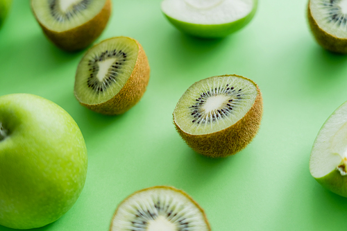 close up view of tasty kiwi and apples on green