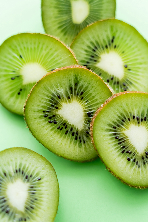 close up view of sliced and fresh kiwi on green