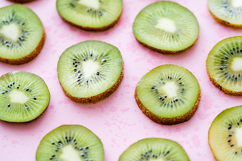 close up view of sliced fresh kiwi on pink
