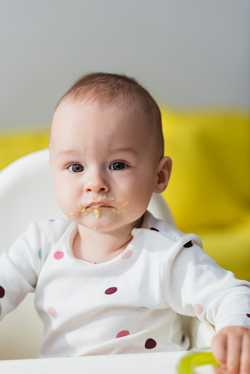 toddler child with food on lips sitting in baby chair