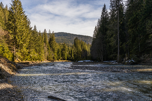 Scenic landscape of mountain river and forest with cloudy sky at background