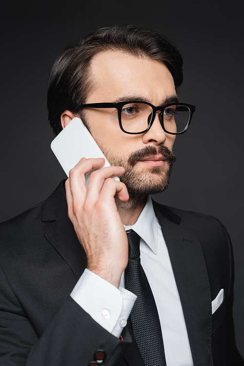 young businessman with mustache talking on smartphone on dark grey