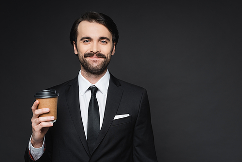 cheerful businessman with mustache holding paper cup on dark grey