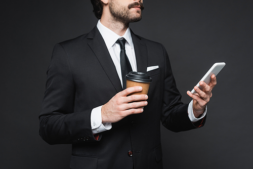 cropped view of businessman with mustache holding paper cup and smartphone on dark grey