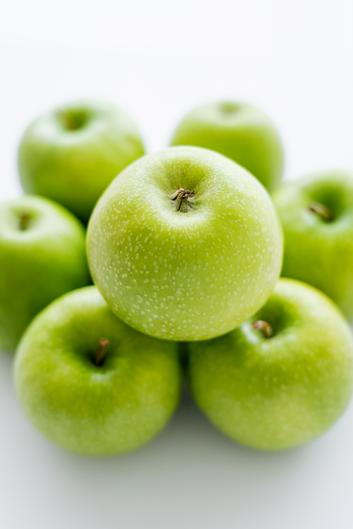 top view of green and ripe apple on blurred pile on white