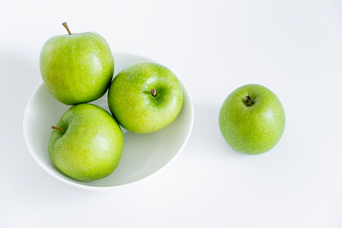 top view of green and organic apples in bowl on white