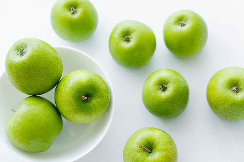 top view of bowl with organic apples on white