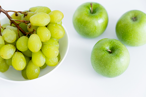 top view of grapes in bowl near apples on white