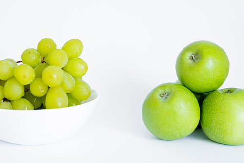 green grapes in bowl near apples on white