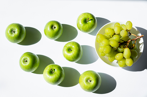 top view of apples near tasty grapes in bowl on white