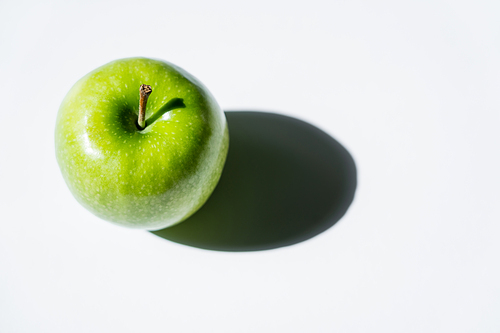 top view of shadow near green apple on white