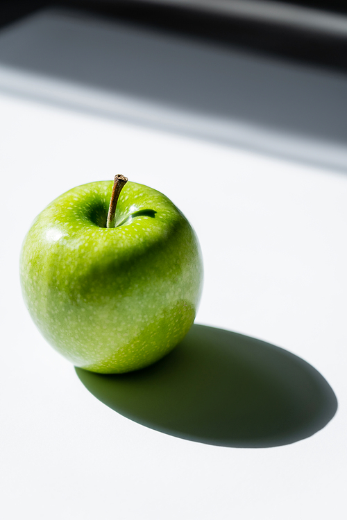 close up of green apple with shadow on white