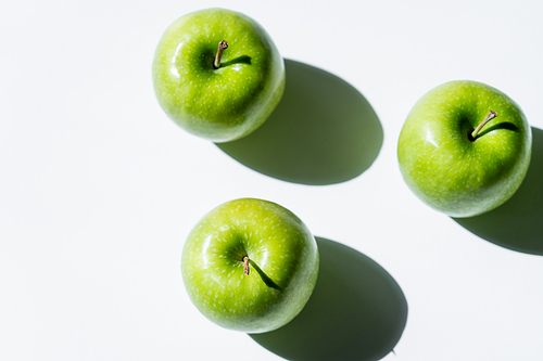 flat lay with green apples with shadows on white