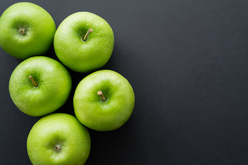 top view of whole and green apples on black