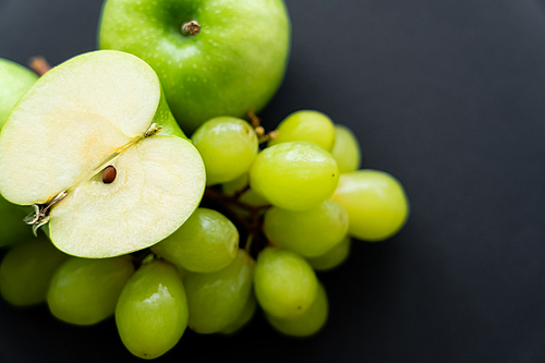 top view of apple half on top on grapes on black