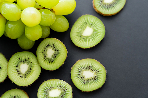 top view of green grapes and sliced kiwi on black