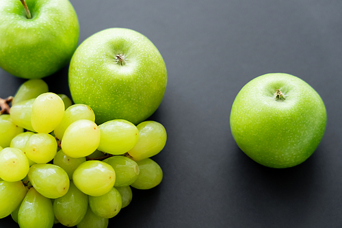 top view of tasty apples near green grapes on black