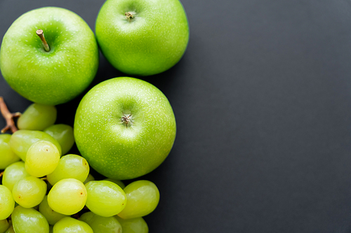 top view of tasty apples and green grapes on black