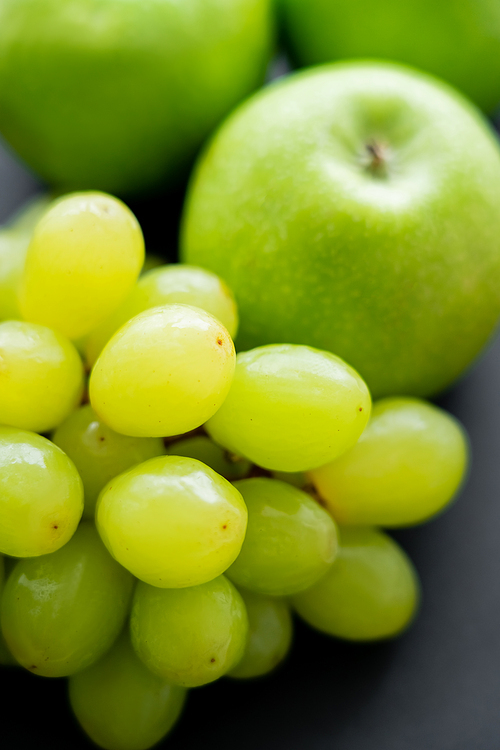 close up view of tasty apples and green grapes on black