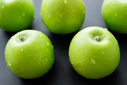 close up view of green and juicy apples with water drops on black