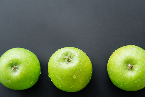 top view of green and fresh apples with water drops on black