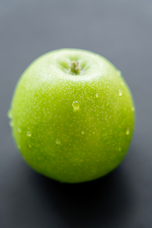 close up view of green and fresh apple with water drops on black