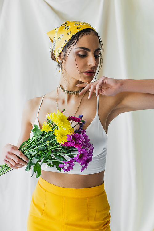 woman in yellow headscarf posing with flowers on white