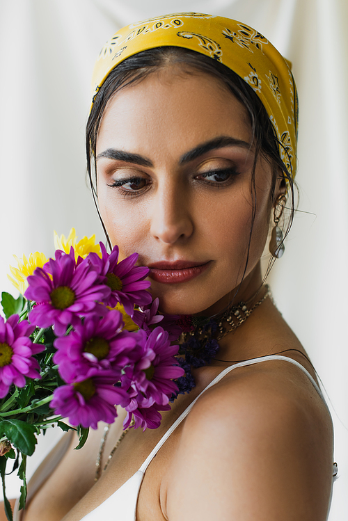 pretty woman in headscarf holding flowers on white