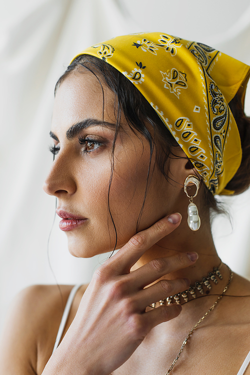 woman in yellow headscarf looking away while posing on white