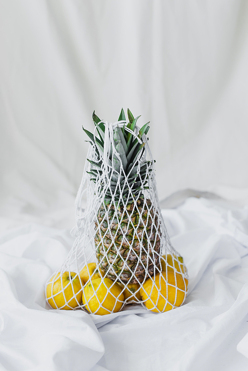reusable string bag with lemons and pineapple on white