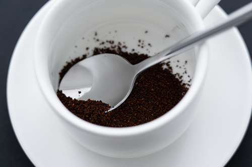 close up view of ground coffee in cup with spoon