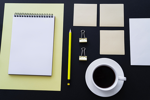 flat lay of cup with coffee near sticky notes, pencil and notebook on black