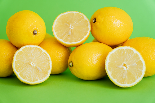 Halves and whole lemons on green background