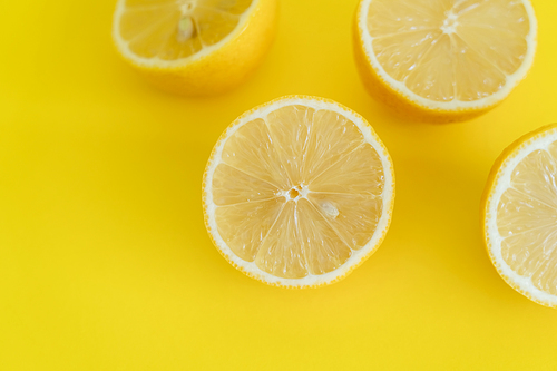 Top view of halves of lemons on yellow background