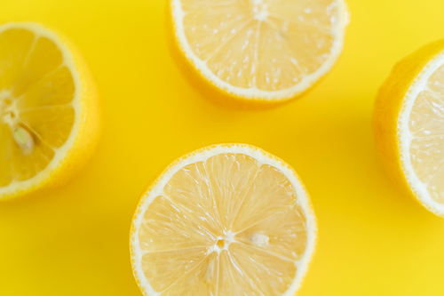 Top view of halves of ripe lemons on yellow background
