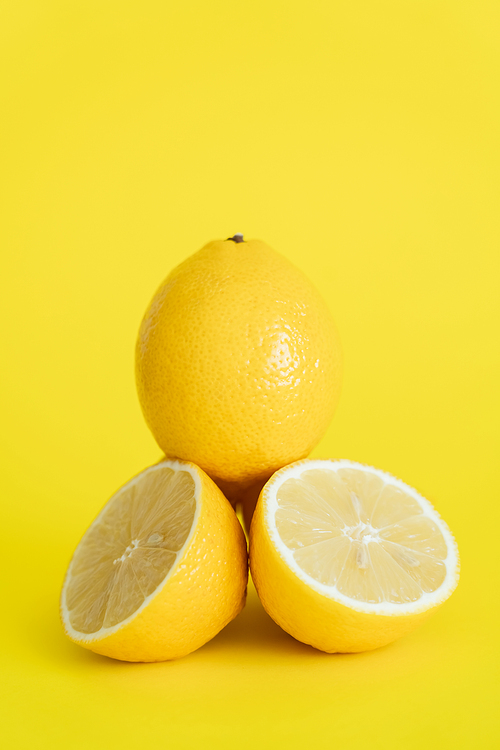 Close up view of cut and whole lemons on yellow background