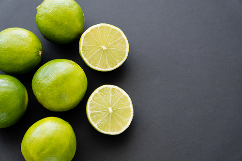 Top view of whole and cut limes on black background with copy space