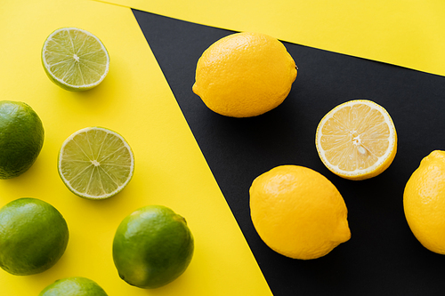 Top view of fresh limes and lemons on black and yellow background