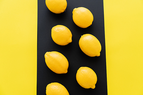 Flat lay with bright lemons on black and yellow background
