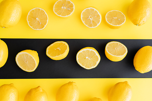 Flat lay of juicy lemons on black and yellow background