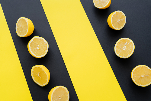 Flat lay with halves of lemons on black and yellow background