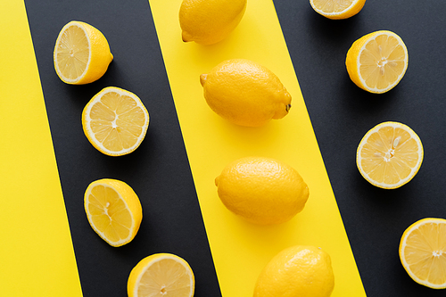 Flat lay with halves and whole lemons on black and yellow background