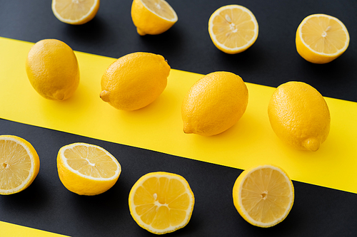 Flat lay of organic lemons on black and yellow background