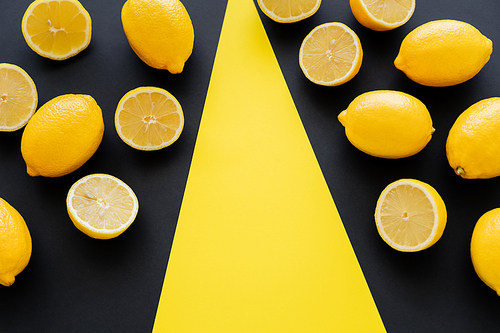Flat lay with juicy lemons on black and yellow background