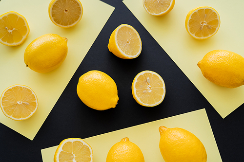 Flat lay with bright lemons on beige and black background