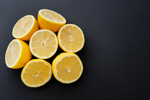 Flat lay of cut lemons on black surface with copy space