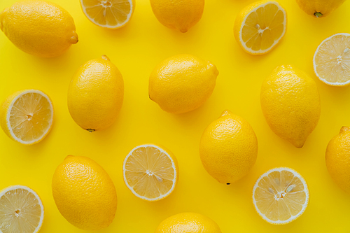 Flat lay of bright lemons on yellow surface