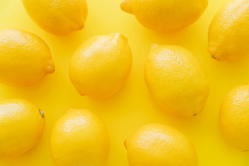 Top view of ripe lemons on yellow surface