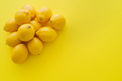 Top view of heap of organic lemons on yellow surface