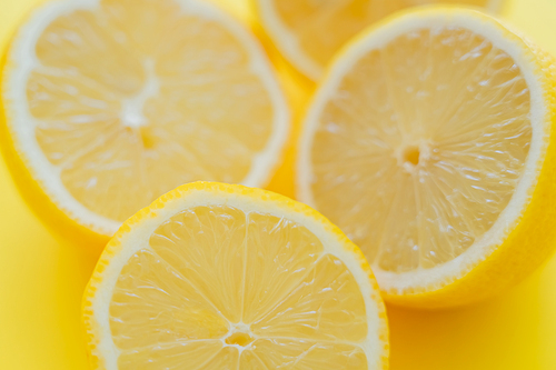 Close up view of blurred halves of lemons on yellow surface